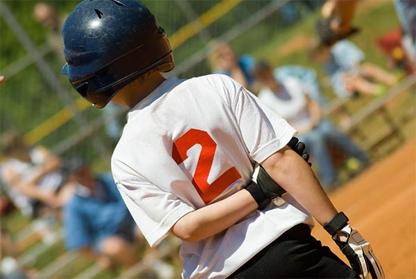 back of young baseball player wearing helmet